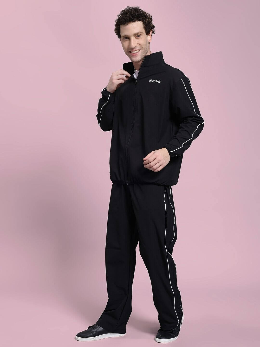 Man wearing RELIGHT RELAXED FIT CO-ORD SET BLACK showcasing thermal-regulating fabric with oversized hoodie and tapered fit on pink background.