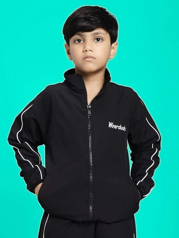 Child wearing RELIGHT RELAXED FIT JACKET FOR BOYS AND GIRLS BLACK with a turquoise background.