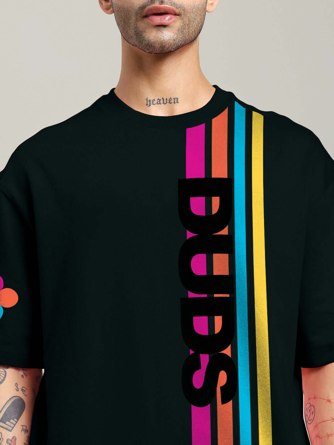 Model wearing a black retro stripes oversized t-shirt with colorful vertical stripes and bold 'DUDS' text, made of premium cotton fabric.