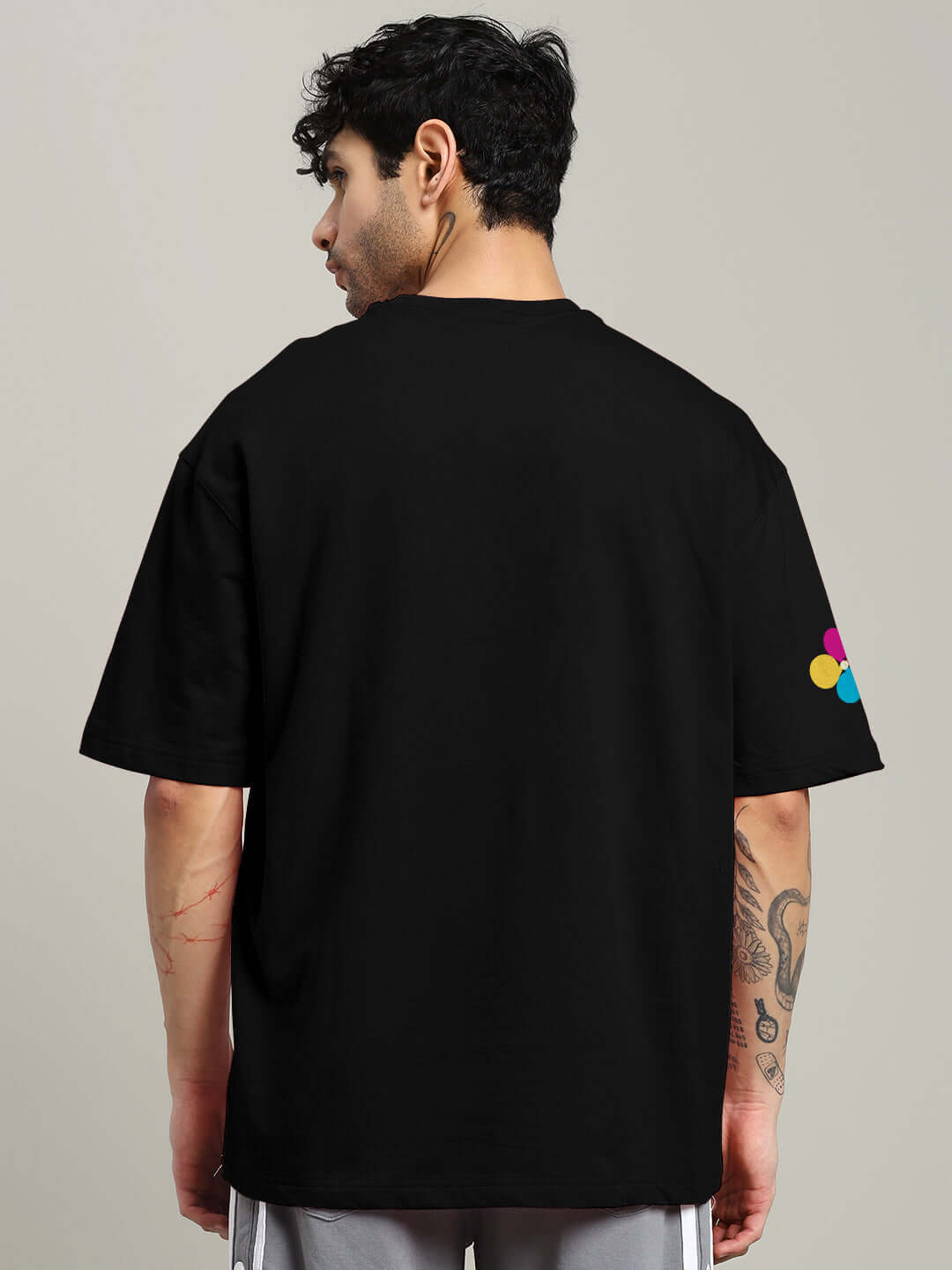 Man wearing a black retro stripes oversized t-shirt with colorful sleeve detail, made of premium cotton fabric.