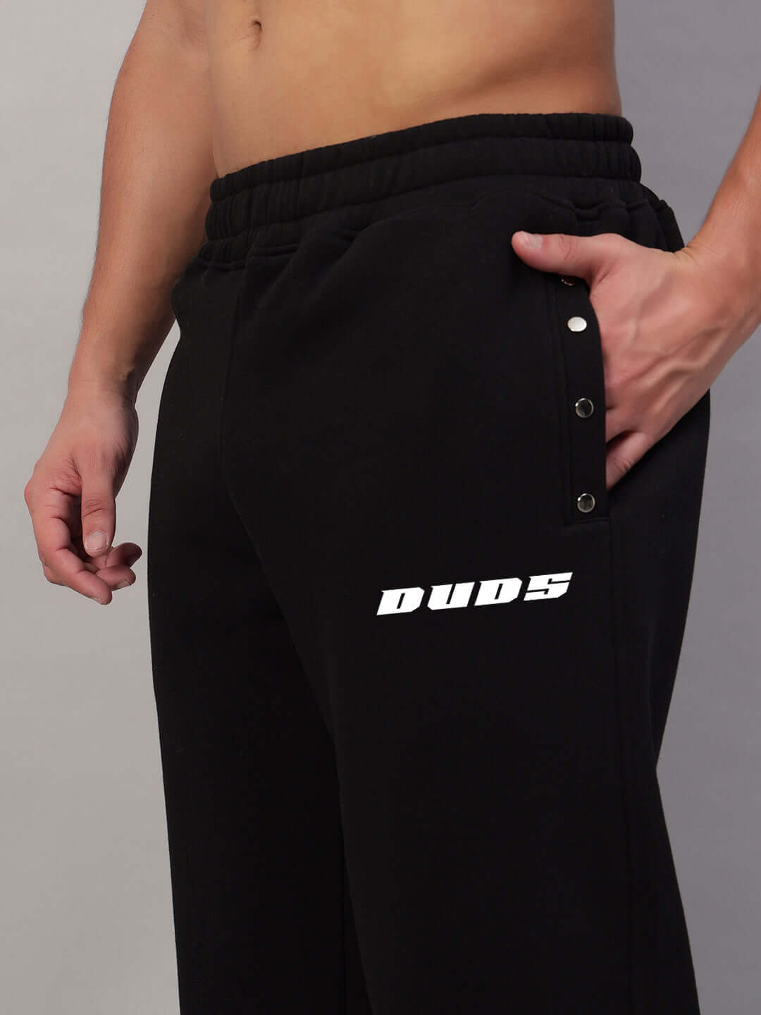 Model wearing black rigid cotton fleece jogger pants with logo, showcasing relaxed fit and tapered ankles.