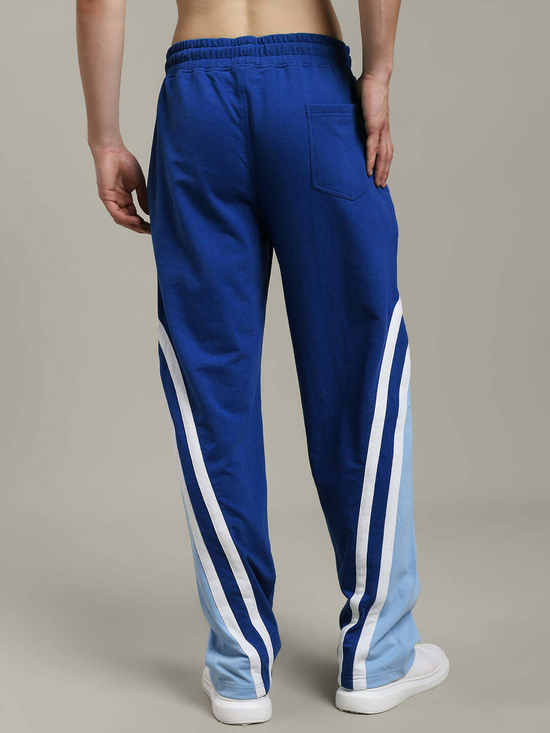 Back view of RIO ONE Relaxed Fit Joggers in blue, featuring white stripe detail, worn by a model.