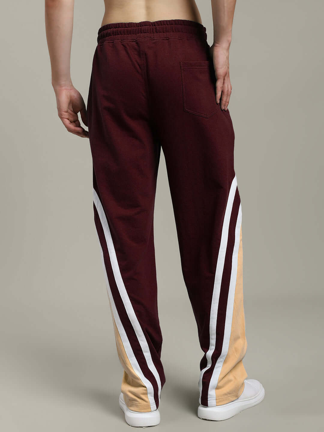 Back view of RIO ONE relaxed fit joggers in brown with white stripes, worn by a model, showcasing comfortable and stylish design.