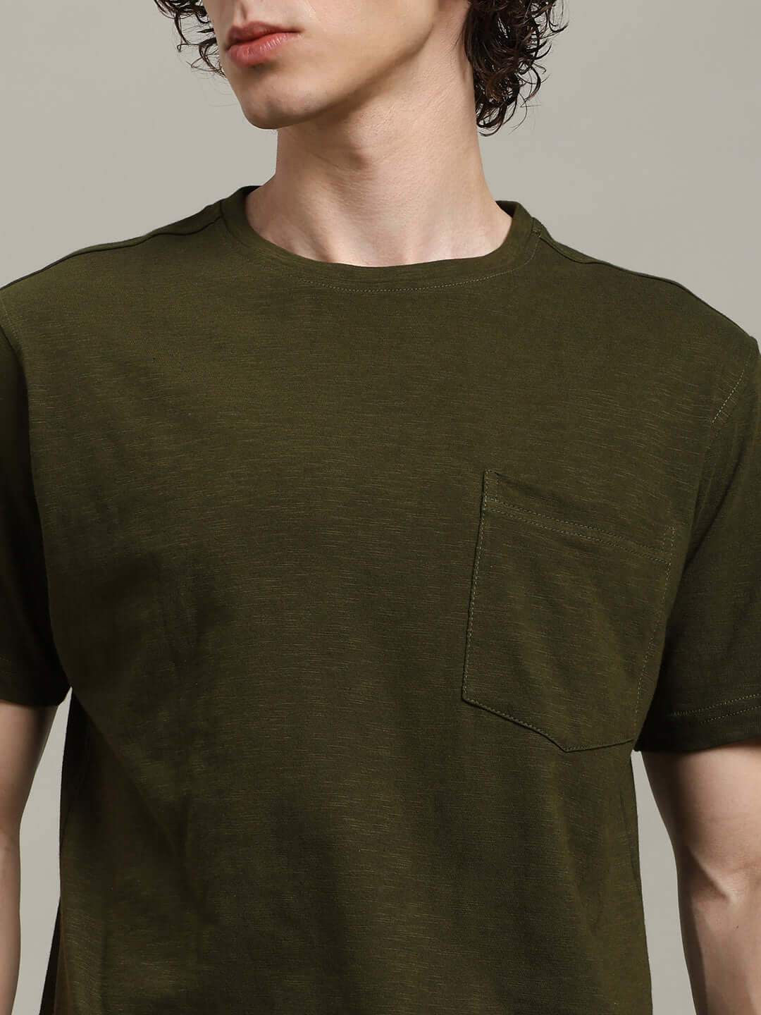 Man wearing ROBAR Regular Fit Olive T-Shirt made of 100% cotton slub with a front pocket; stylish and comfortable design.