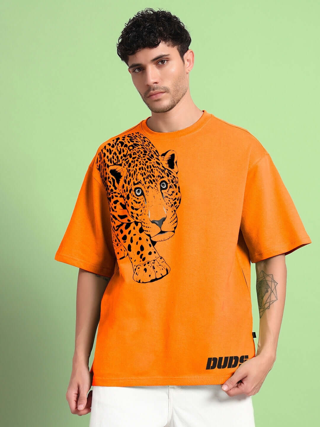 Man wearing ROBERTO LEOPARD PRINTED T-SHIRT ORANGE featuring a leopard graphic on orange background, fashion streetwear style.