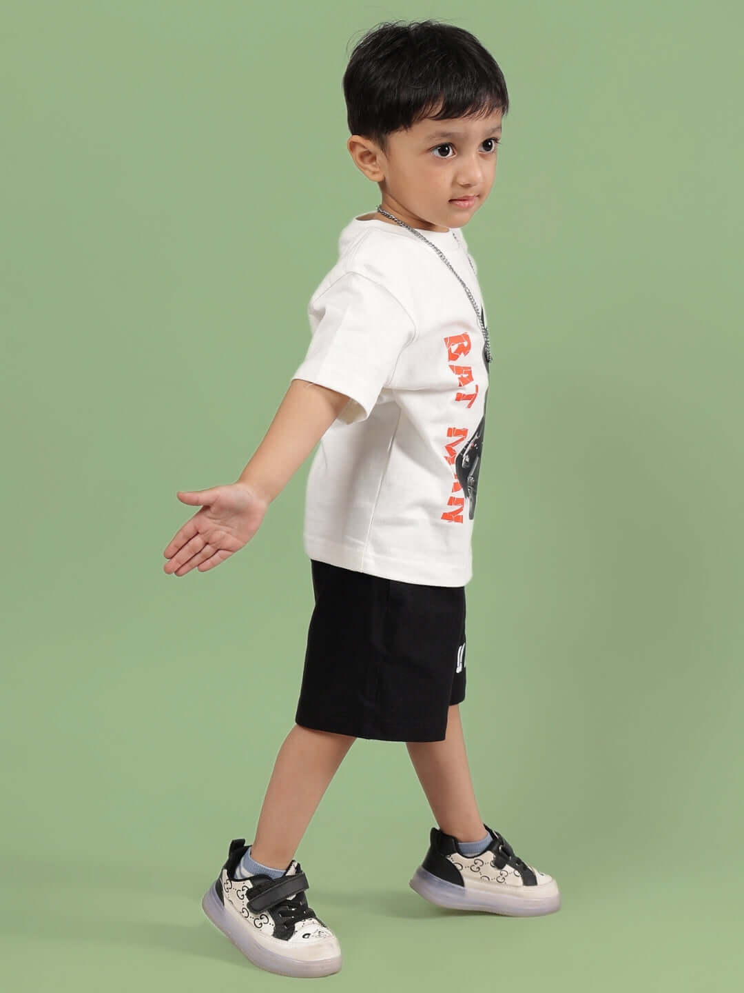 Child wearing ROBIN CO-ORD FOR BOYS & GIRLS OFF WHITE-BLACK by DUDS, standing in stylish outfit on green background, made to order.