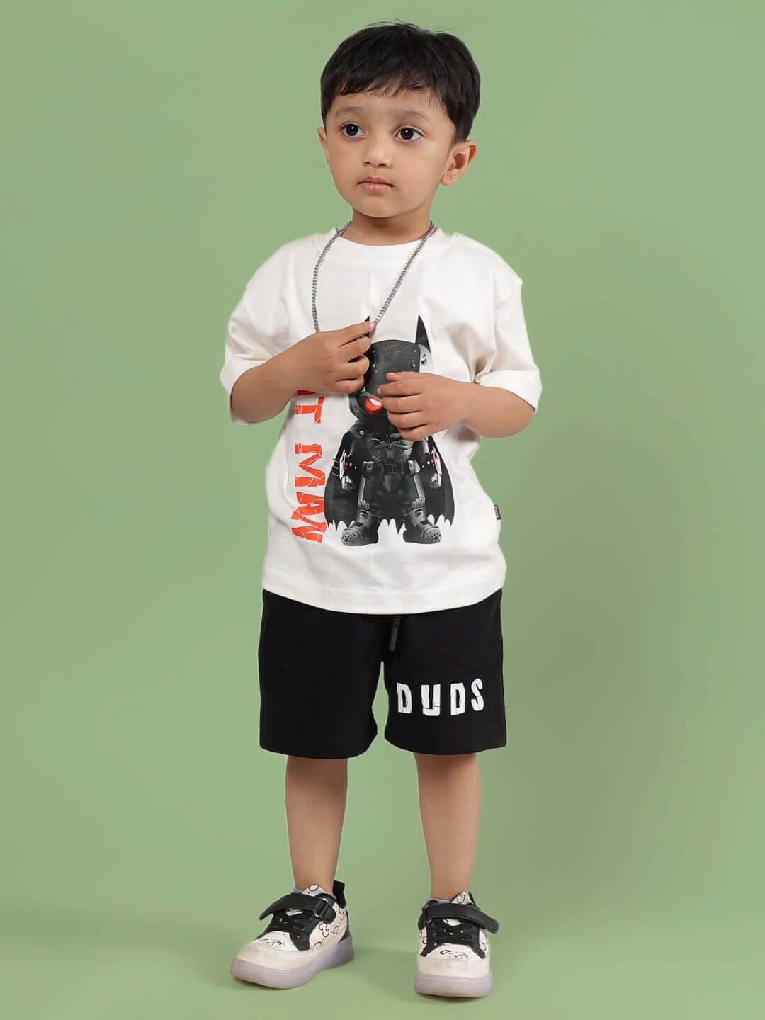 Child wearing ROBIN CO-ORD FOR BOYS & GIRLS OFF WHITE-BLACK, DUDS brand, standing against green background.