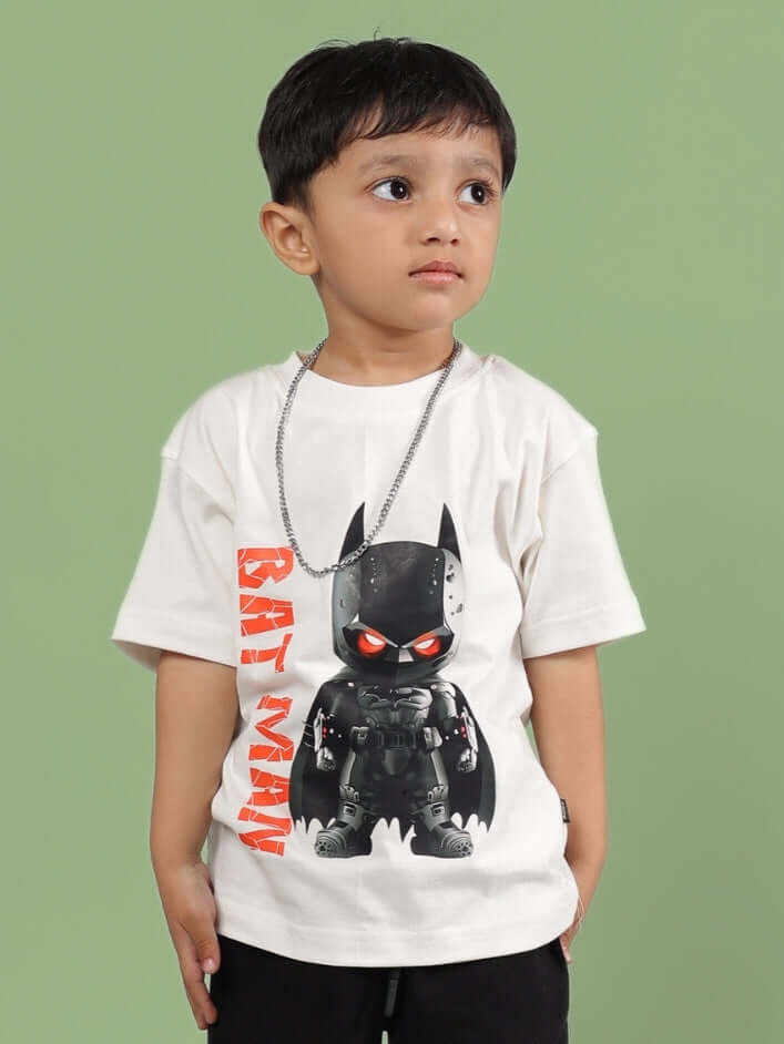 Child wearing ROBIN T-SHIRT FOR BOYS GIRLS OFF WHITE with cartoon print, standing against green background, exuding comfort and style.