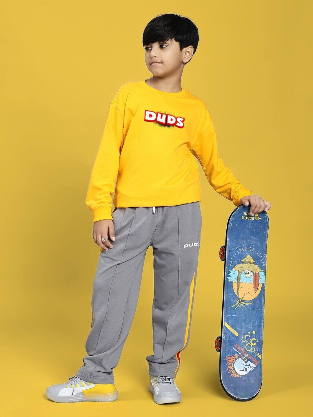 Child wearing the ROBLOX SWEATSHIRT FOR BOYS AND GIRLS YELLOW, posing with skateboard on a vibrant background.