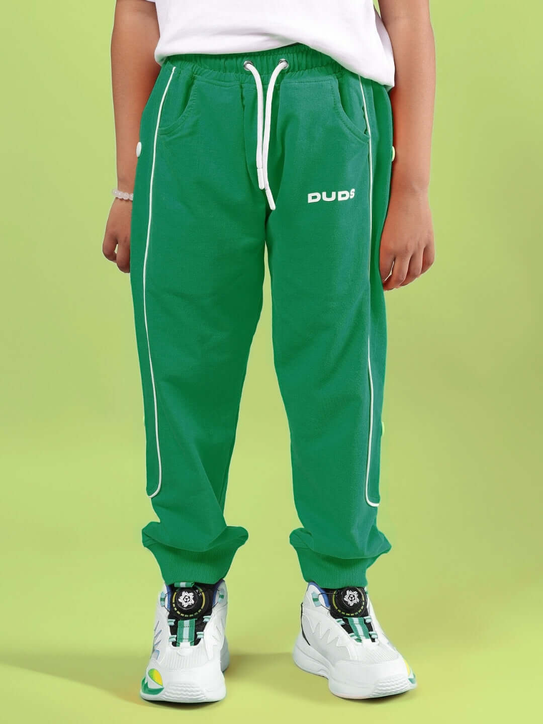 Child wearing ROBO REX CO-ORD FOR BOYS & GIRLS WHITE-GREEN pants with white sneakers on light green background.