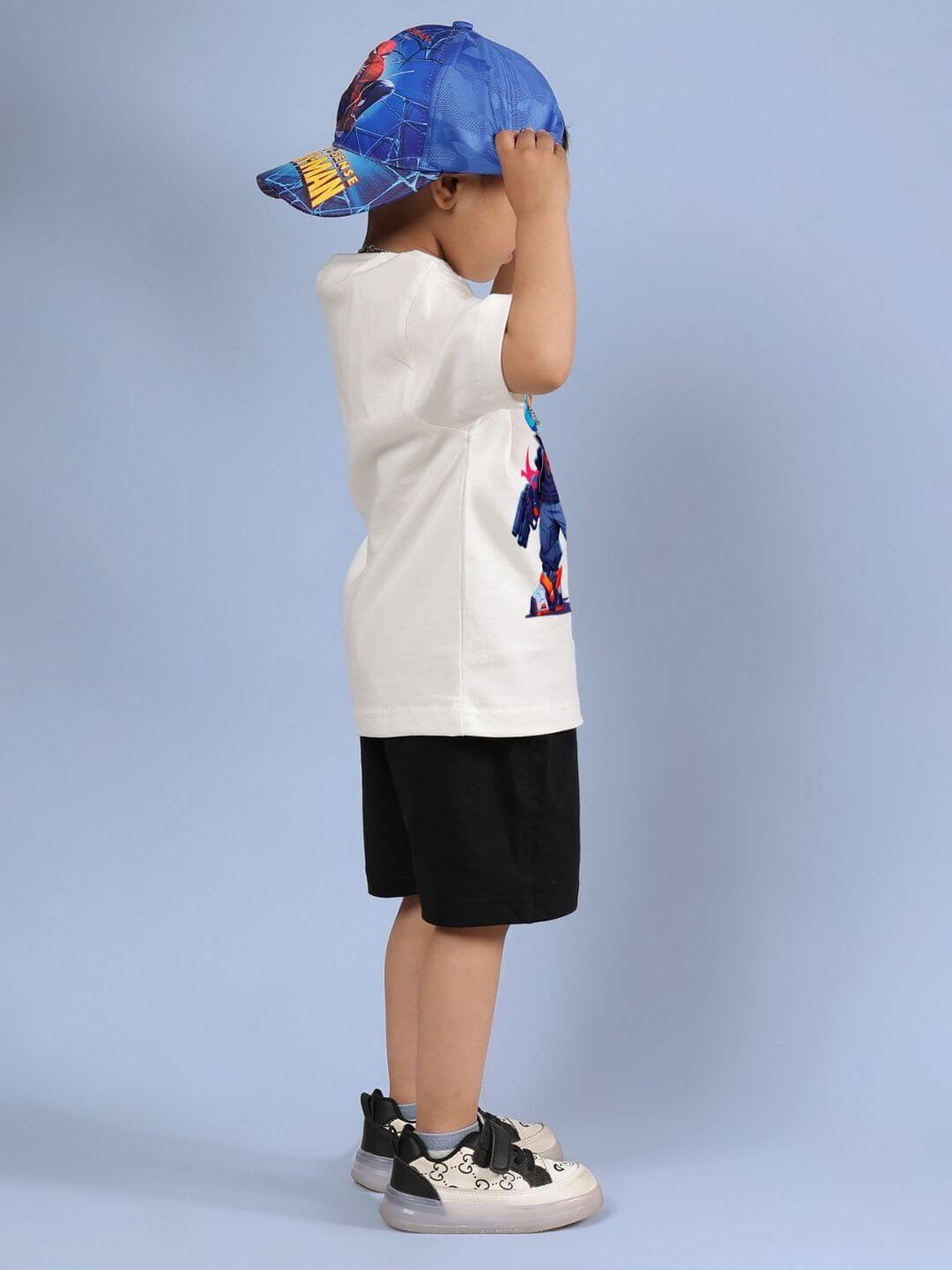 Child wearing Robo Super Co-ord Set, featuring off white T-shirt and black shorts, standing sideways on a blue background.