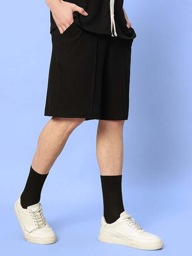 Men wearing ROBSON REGULAR FIT SHORTS BLACK with white sneakers and black socks, showcasing the style and fit of the shorts.
