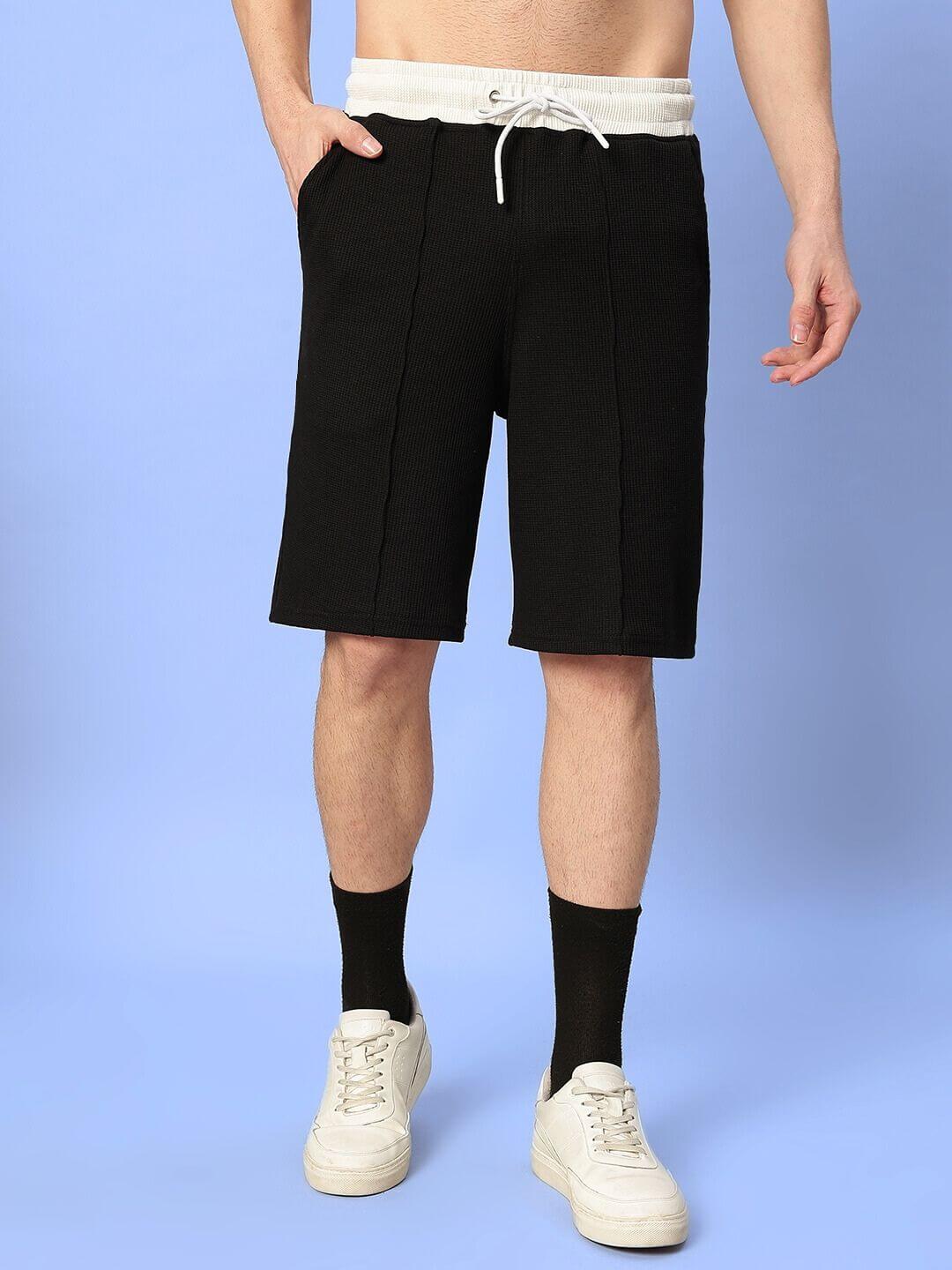 Men wearing ROBSON REGULAR FIT SHORTS BLACK, standing against a blue background, showcasing stylish casual wear with a customizable fit option.