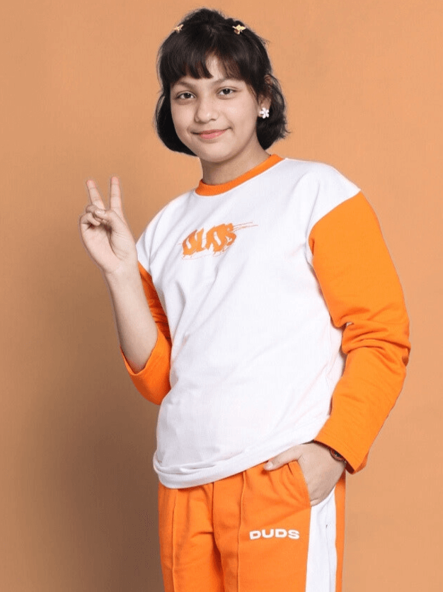 Child wearing white-orange oversized sweatshirt from Color By Colours, showcasing peace sign against orange background.