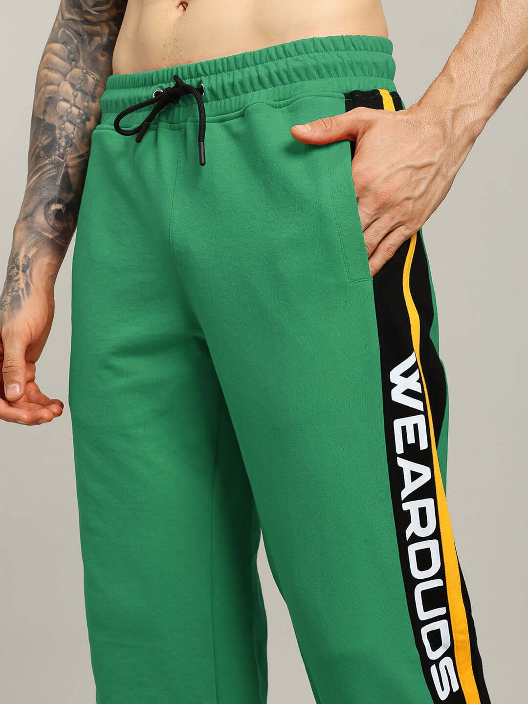 Close-up of model wearing ROGER RELAXED-FIT JOGGERS GREEN with black side stripes and elastic waistband.