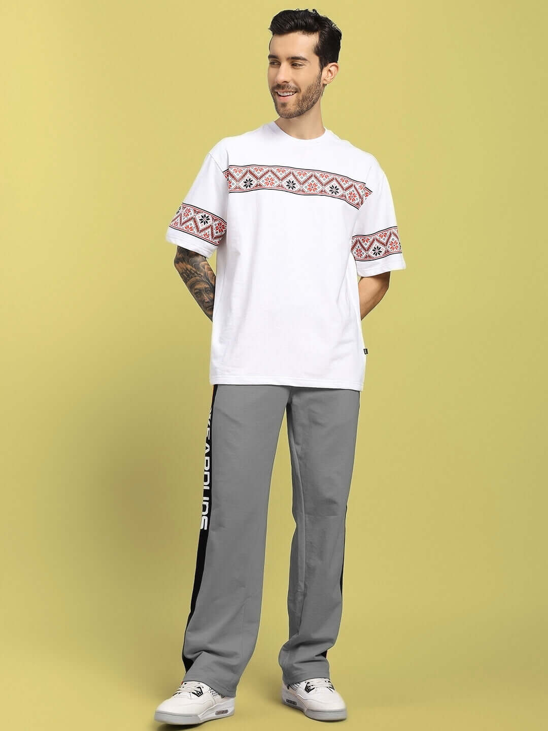 Model wearing grey ROGER relaxed-fit joggers with custom fit option, paired with a white patterned T-shirt.