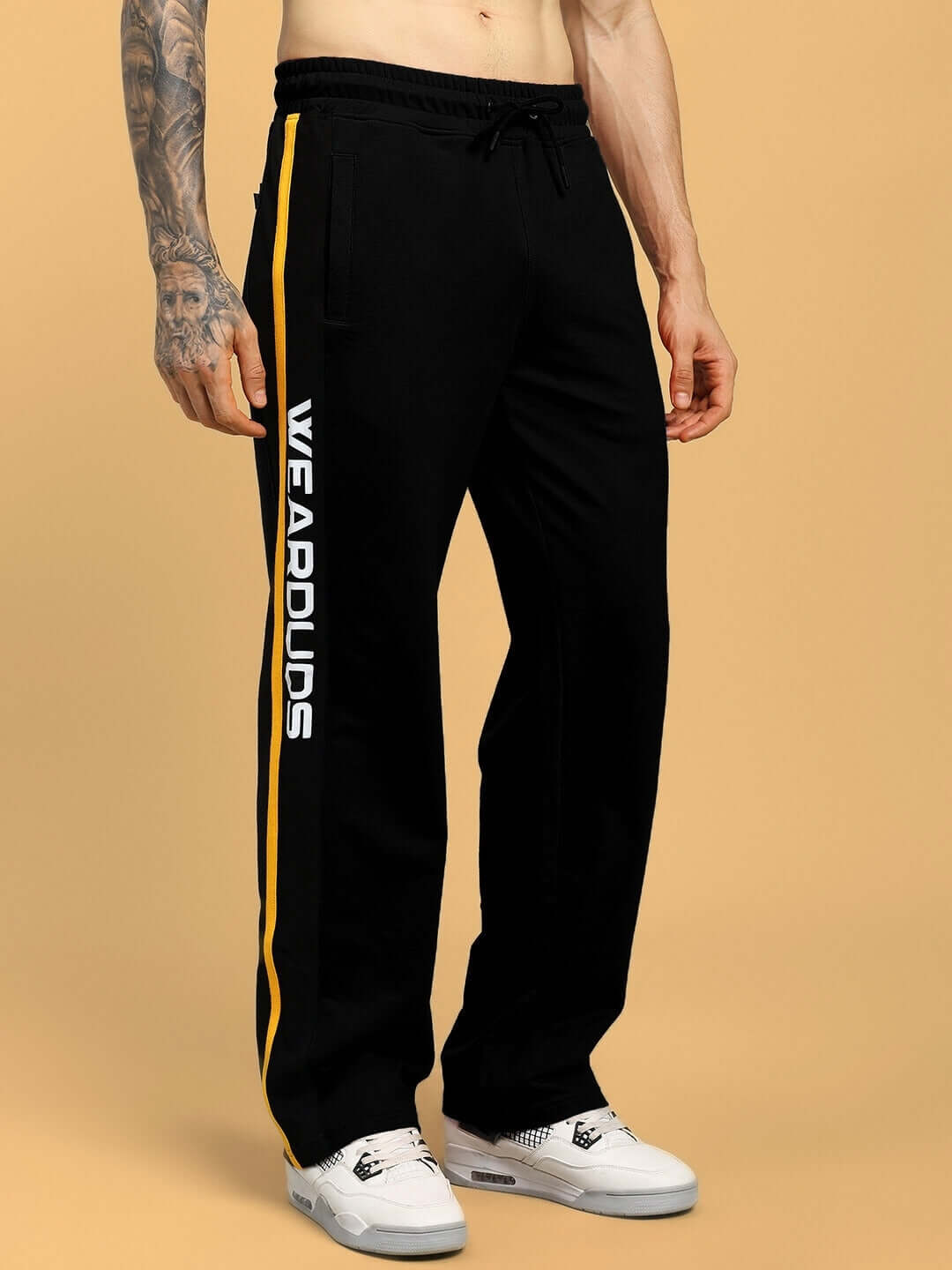 Model wearing ROGER RELAXED-FIT JOGGERS BLACK with side stripes and logo, showcasing streetwear style.