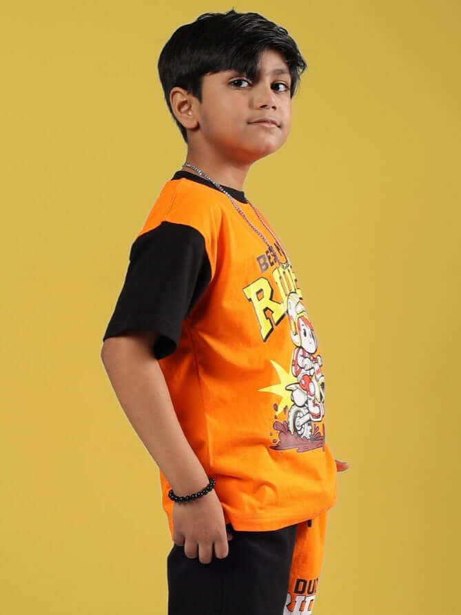 Boy wearing ROGUE RIDER T-SHIRT FOR BOYS GIRLS BLACK-ORANGE, showcasing its bold black and orange design on a yellow background.
