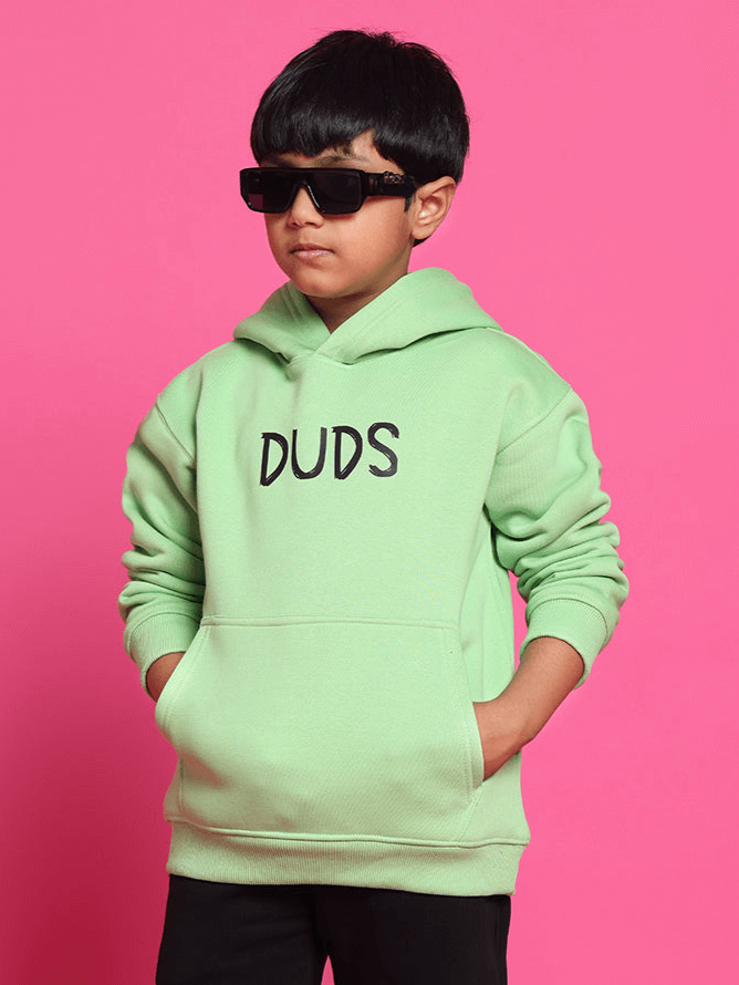 Child wearing ROOAR oversized neon green hoodie with black print on pink background.