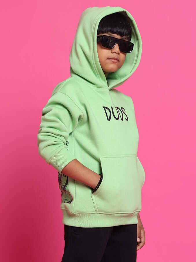 Child wearing neon green ROOAR oversized hoodie with sunglasses, standing against a pink background.