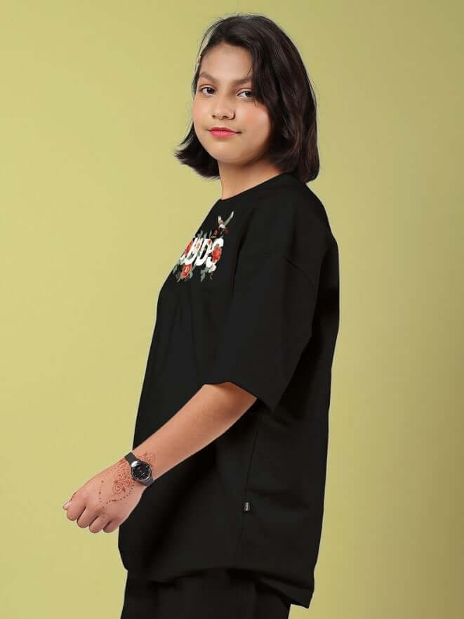 Child wearing ROSE CHARM OVERSIZED T-SHIRT FOR BOYS AND GIRLS BLACK showcasing street-chic style and rose charm detail.