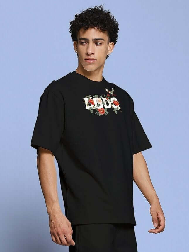 ROSE CHARM OVER-SIZED T-SHIRT BLACK with edgy rose graphic worn by model, showcasing street style and premium cotton comfort.