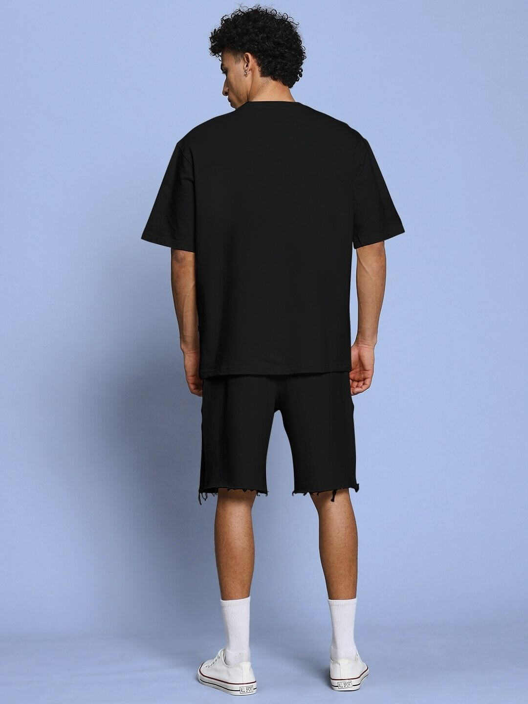 Back view of model wearing ROSE CHARM RELAXED FIT CO-ORD SET BLACK against blue background, showcasing casual sophistication.