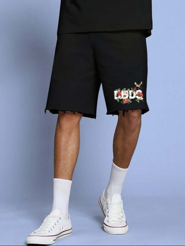 Person wearing ROSE CHARM RELAXED FIT SHORTS BLACK, showcasing easygoing fashion with comfort and style, against a blue background.