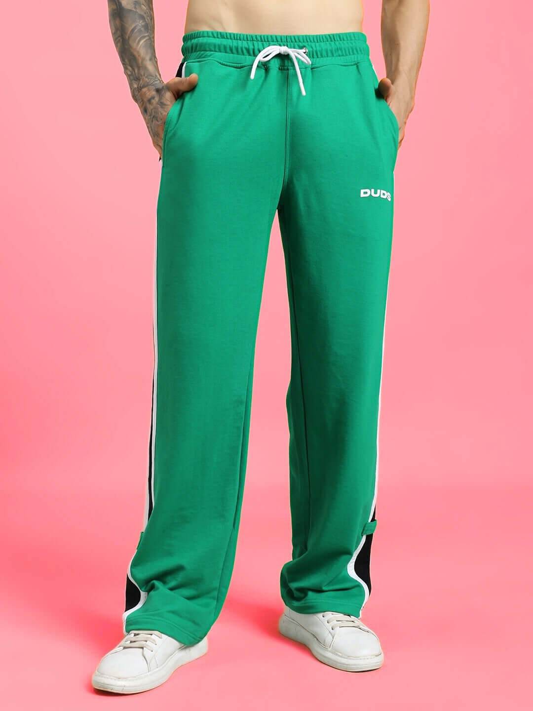 Man wearing ROSSTON FLAT-OUT RELAXED FIT JOGGERS GREEN against pink background showcasing comfortable streetwear style.