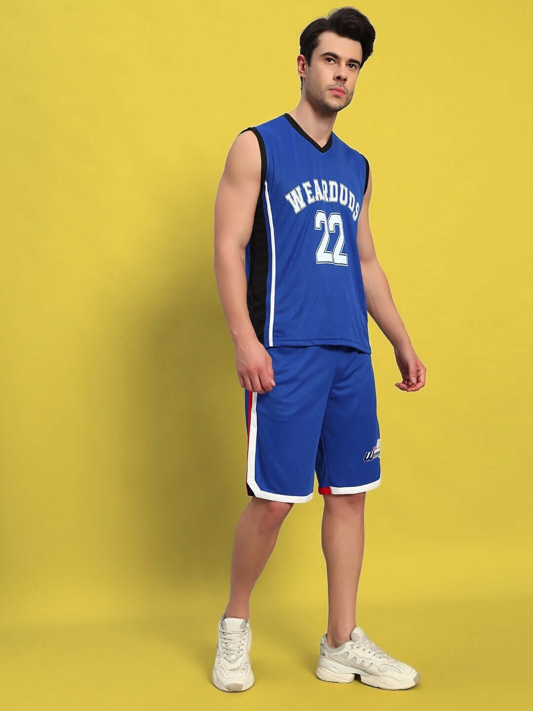 Man wearing royal blue sports co-ord set against a yellow background.