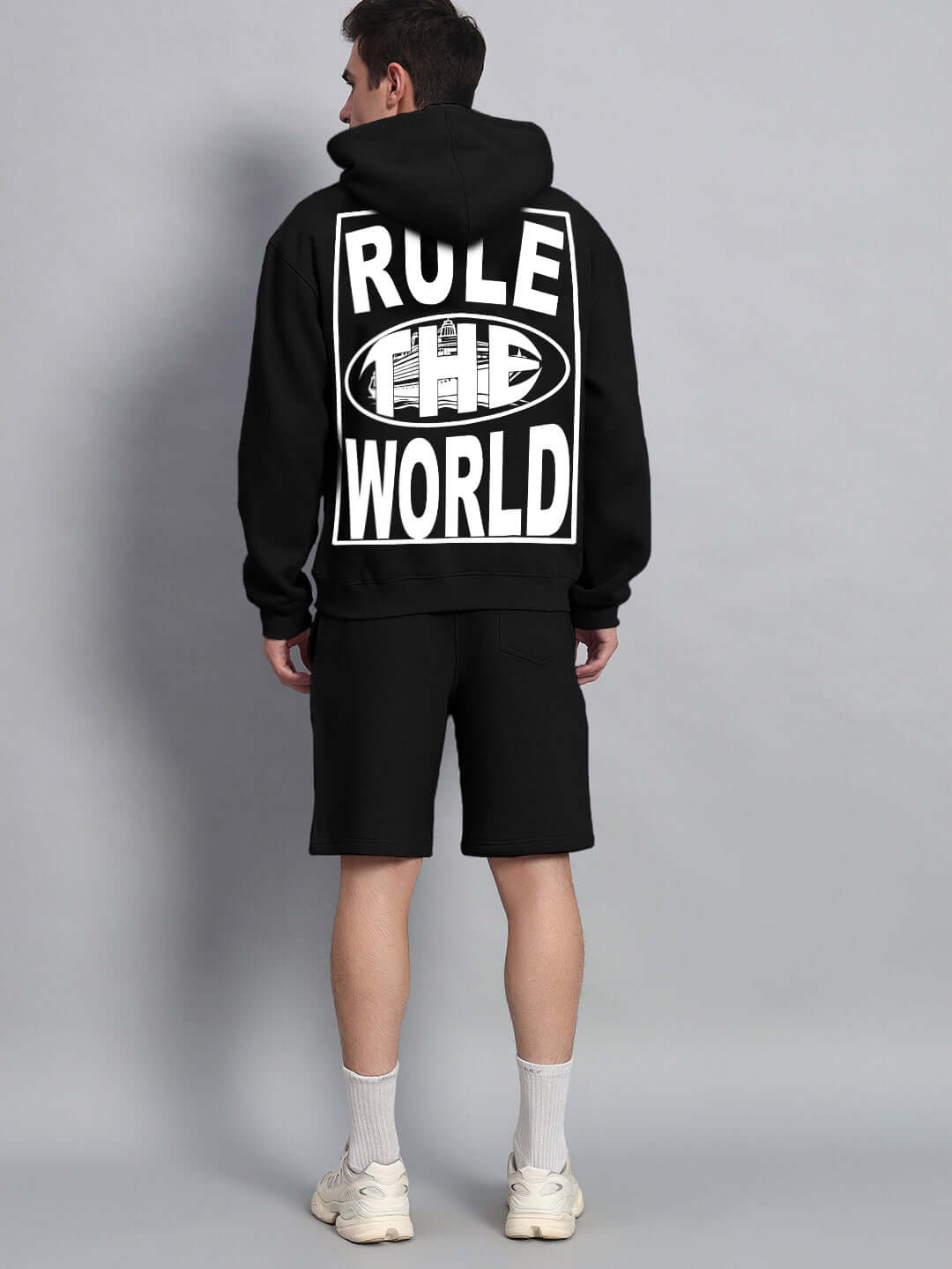 Rear view of a model wearing RULE THE WORLD FLEECE CO-ORD - BLACK, showing bold graphic design, premium fleece fabric, and casual style.