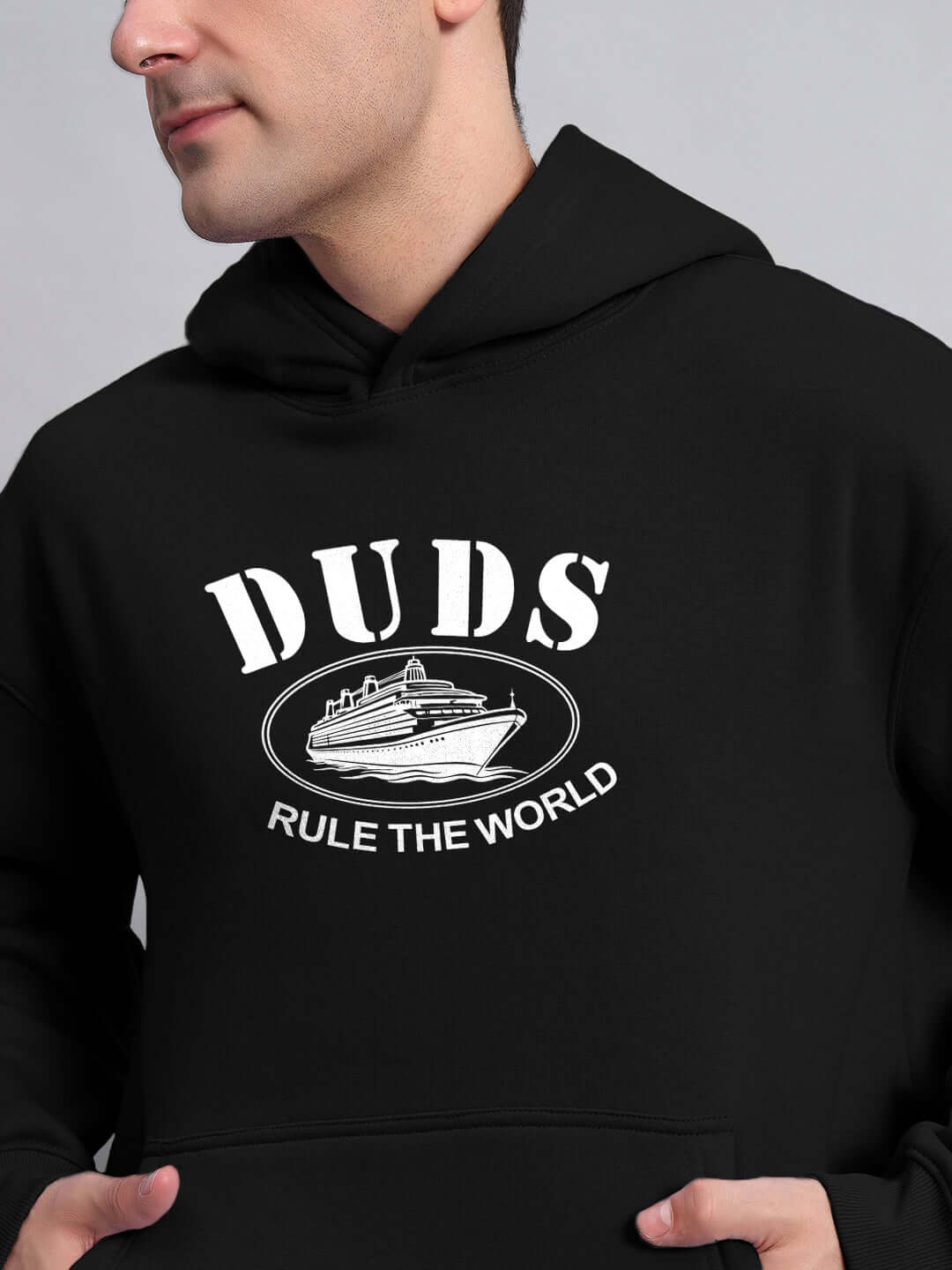 Person wearing RULE THE WORLD OVERSIZED HOODIE BLACK with bold design in streetwear style.