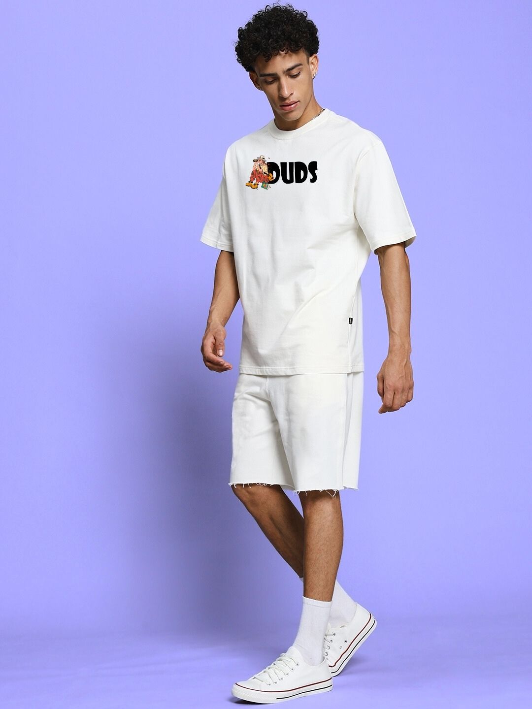 Model wearing SAFARI PRINTED CO-ORD SET OFF-WHITE featuring safari-inspired prints on an oversized tee and matching shorts against a purple background.