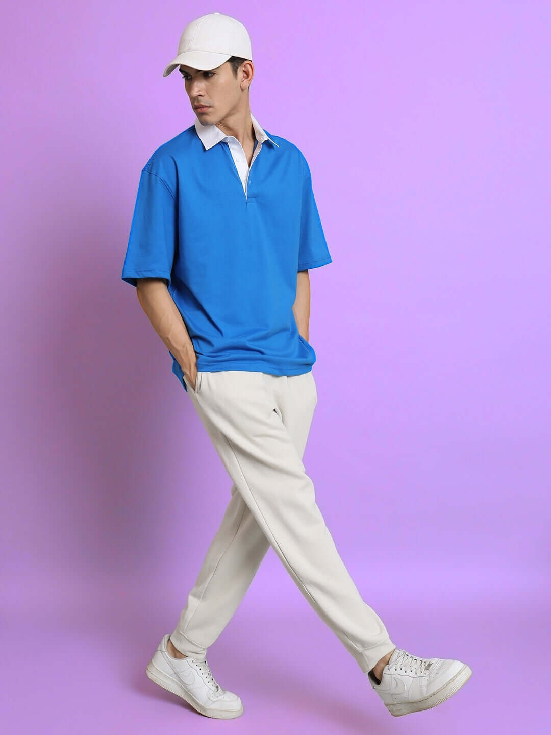 Model wearing oversized royal blue polo t-shirt and cap with casual pants; premium cotton, comfortable fit; perfect for daily wear.