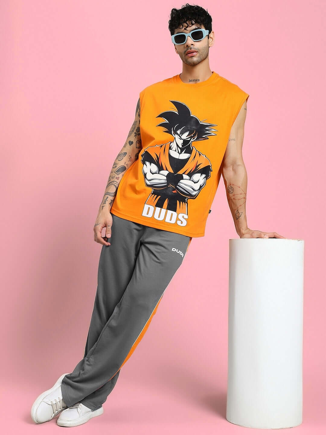 Person wearing SANFORD STRIPE JOGGERS IN GREY with bold side stripes on a sleek grey base, leaning against a white pillar.