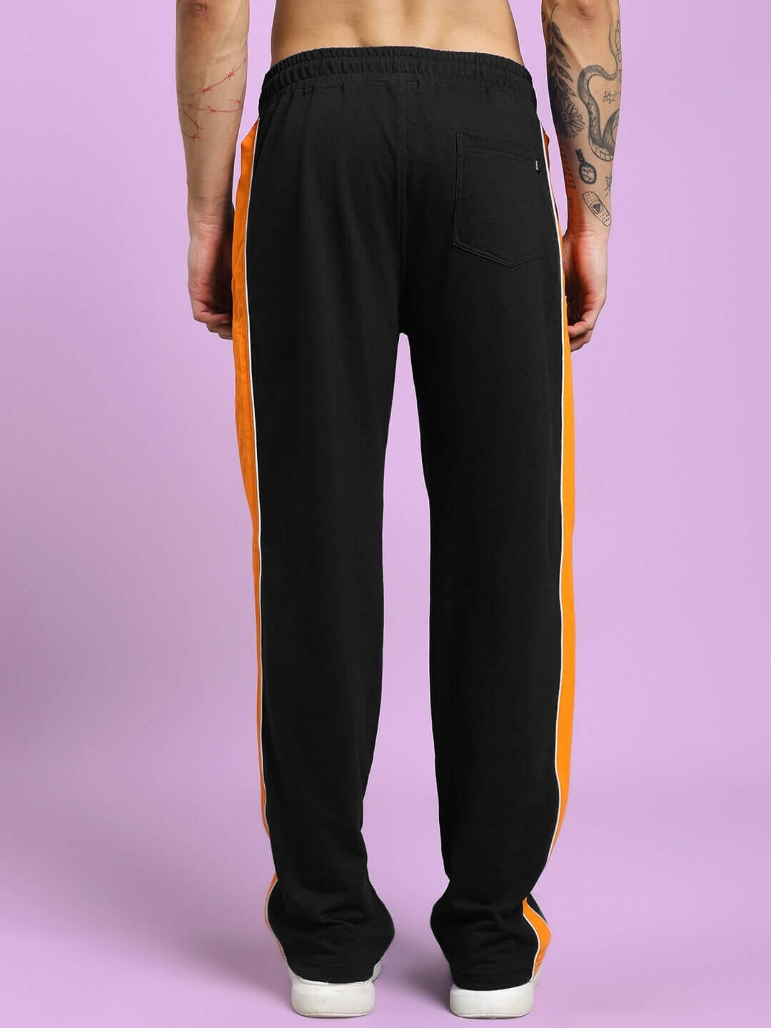 Back view of SANFORD STRIPE JOGGERS IN BLACK with bold orange side stripes, showcasing streetwear style.