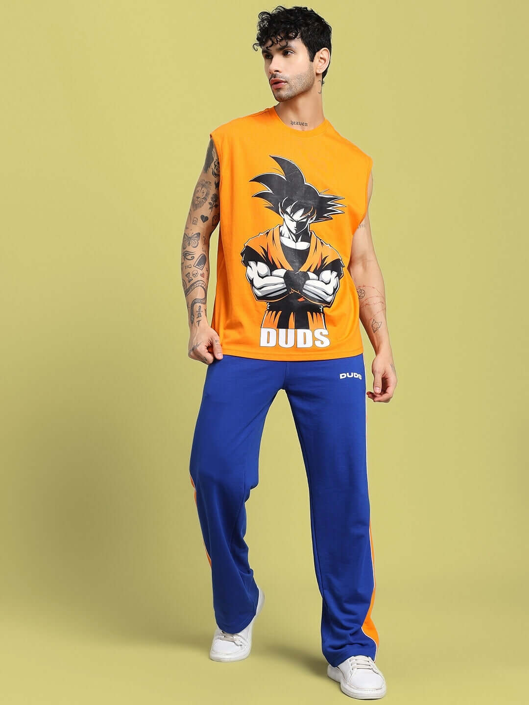 Man wearing SANFORD STRIPE JOGGERS BLUE paired with an orange anime-inspired gym t-shirt, standing confidently on a beige background.