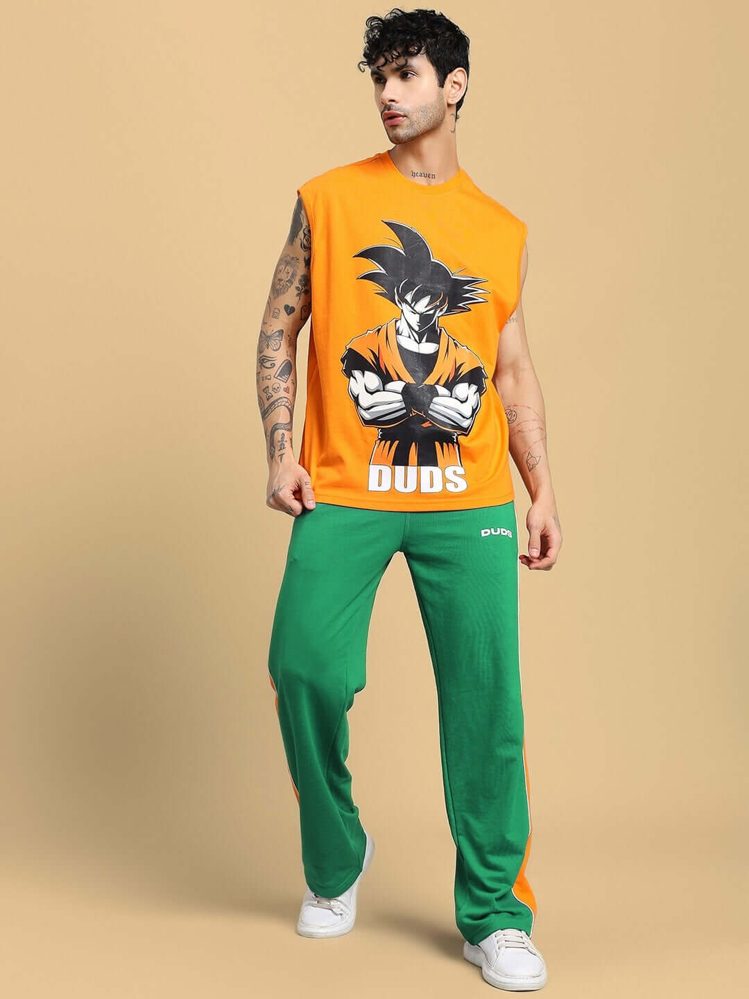 Model wearing SANFORD STRIPE JOGGERS IN GREEN with side stripes, paired with a graphic orange sleeveless top, showcasing streetwear style.