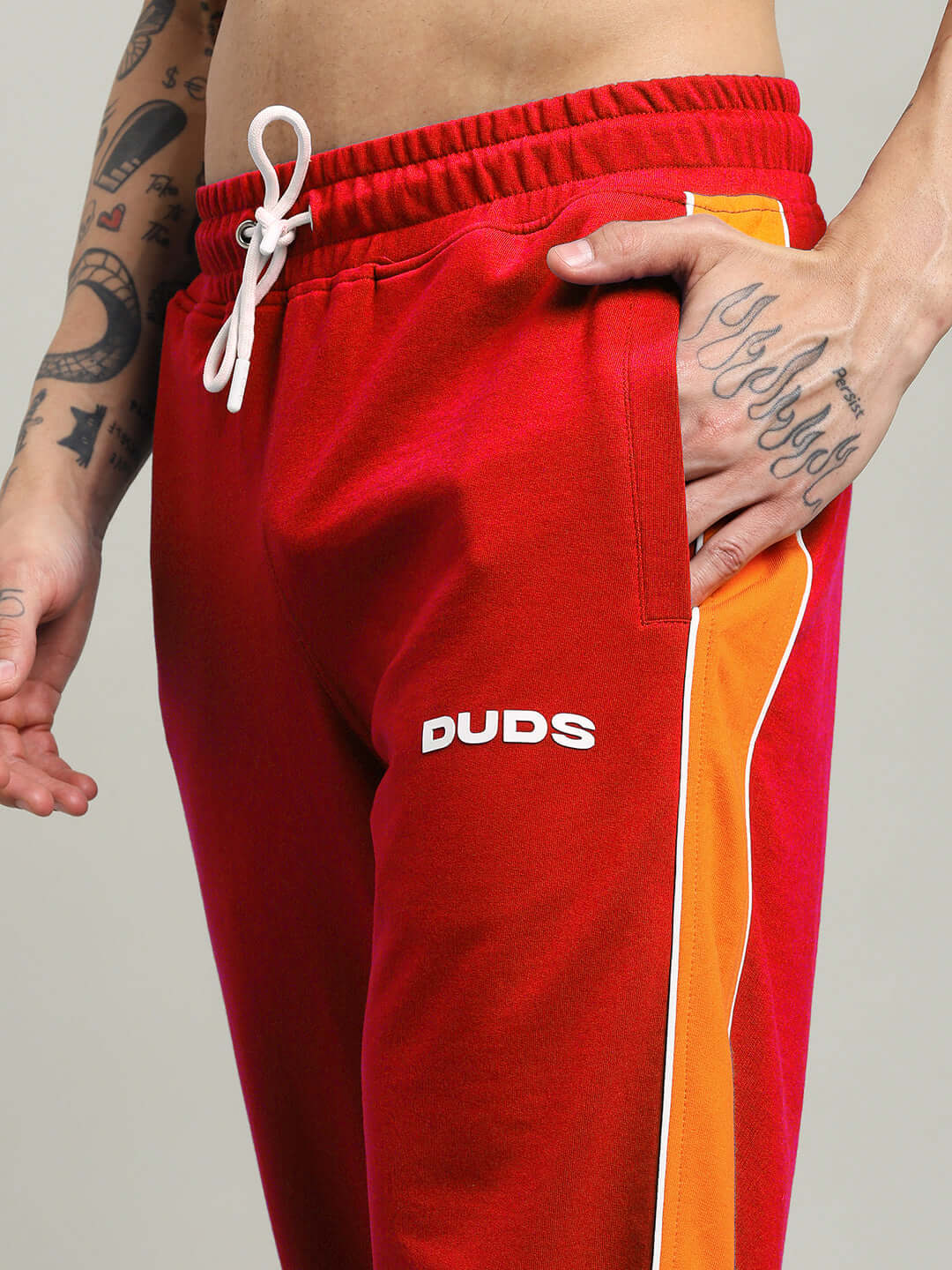 Red SANFORD STRIPE JOGGERS with sleek orange and white side stripes, perfect for streetwear and sporty outfits.