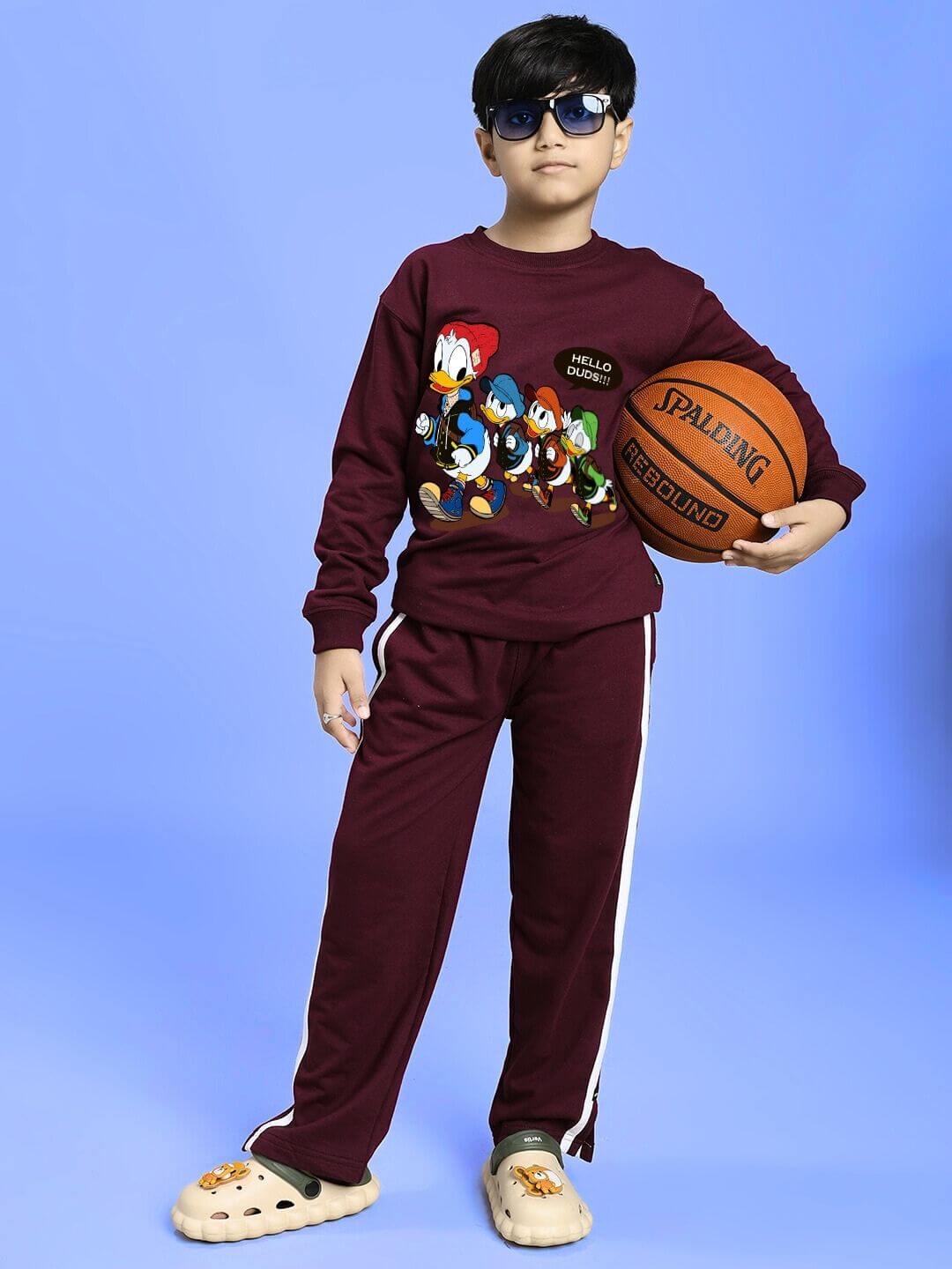 Child wearing SCHOOL DAYS SWEATSHIRT FOR BOYS AND GIRLS MAROON with cartoon characters, holding a basketball.