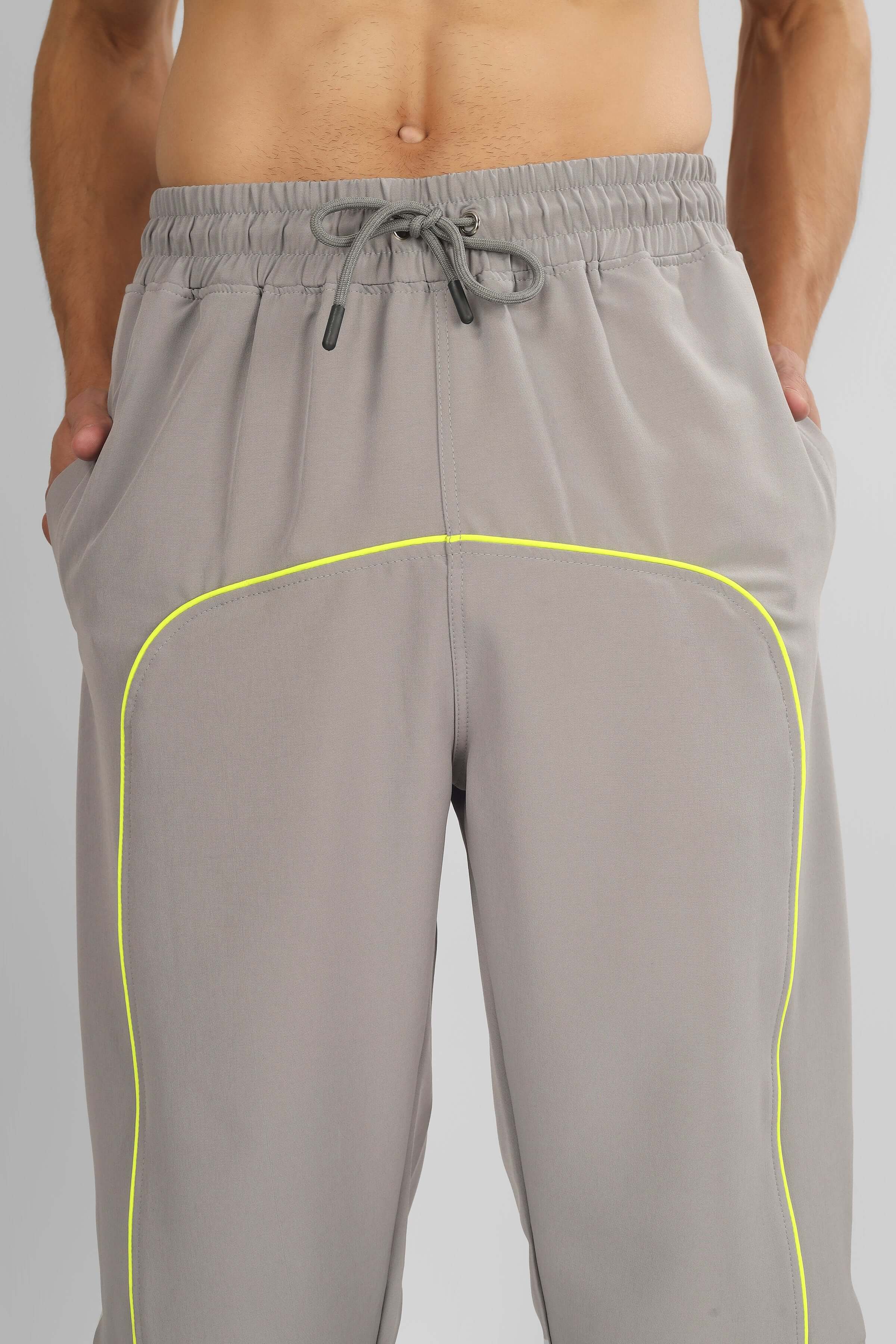 Men's grey parachute cargo pants with drawstring, featuring neon piping. Custom fit available. Shop stylish and comfortable pants online.