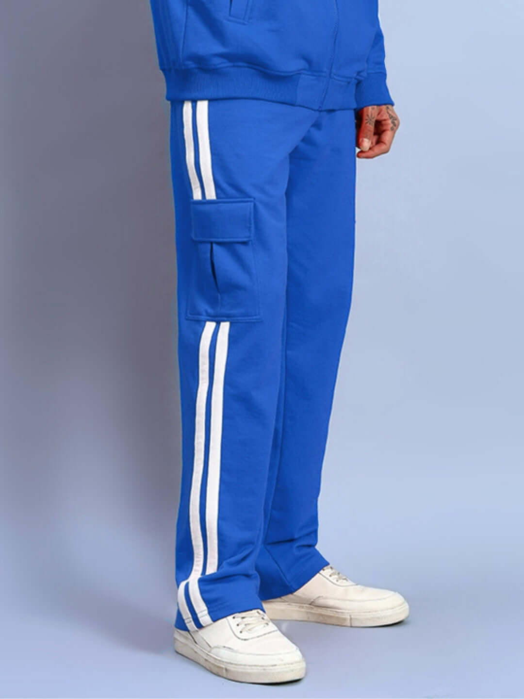 Person wearing royal blue SCOTIA STRIPE joggers with white stripe detailing and cargo pockets, paired with casual white sneakers.