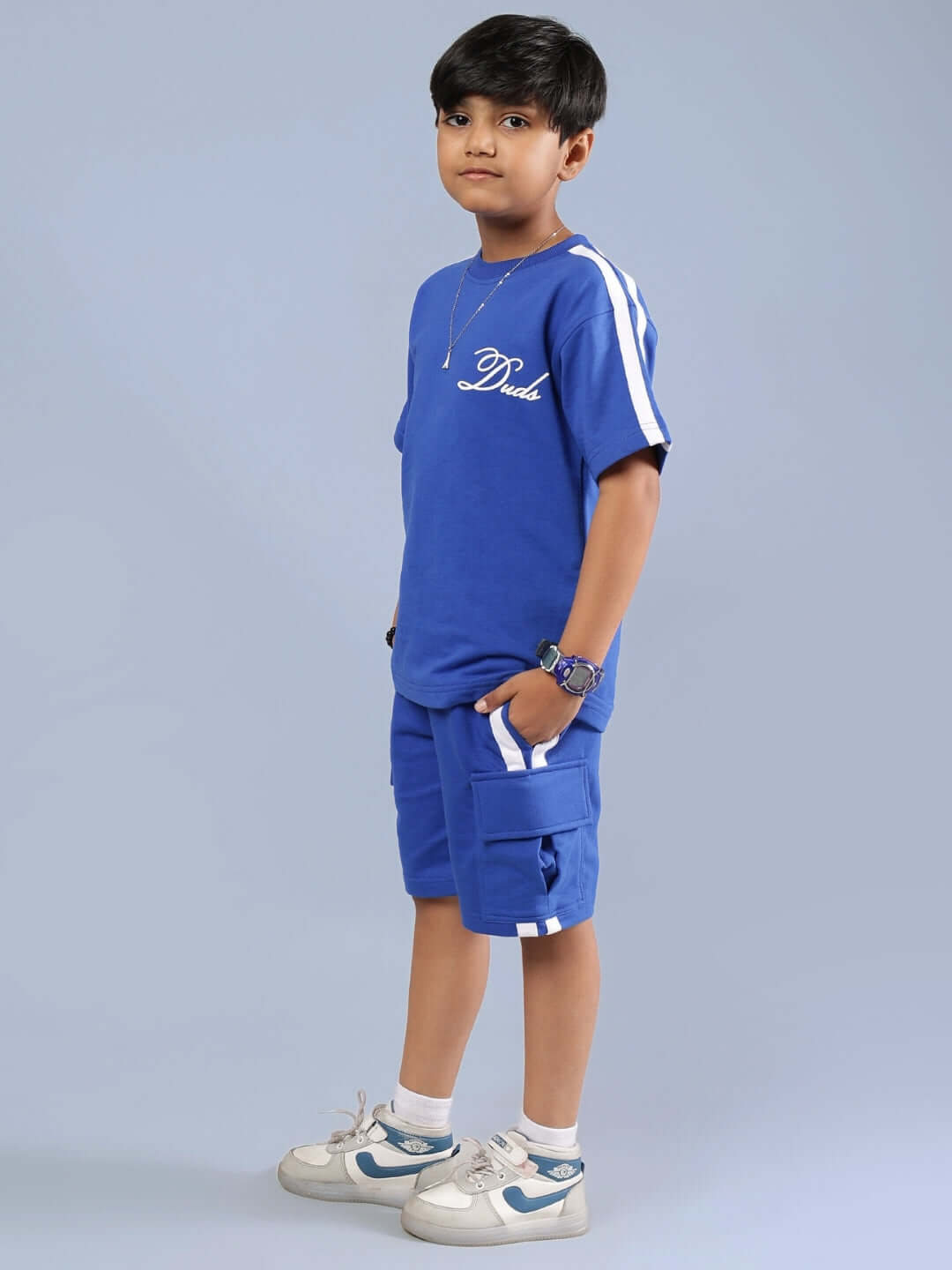 Child wearing Scotia Summer Co-ord in royal blue by DUDS, featuring shorts and a top, perfect for boys and girls. Custom fit available.