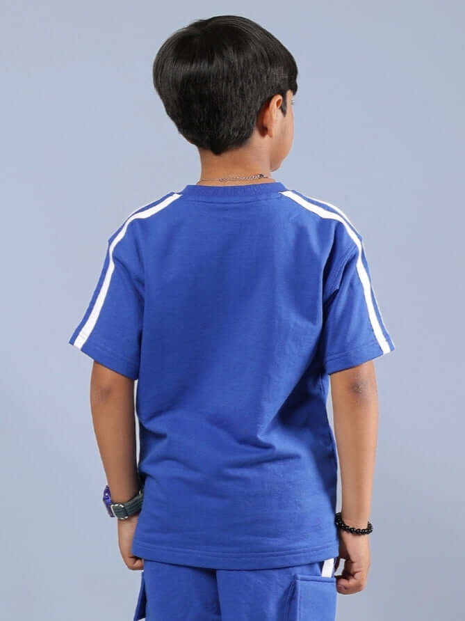 Child wearing SCOTIA T-SHIRT FOR BOYS & GIRLS ROYAL BLUE, showing back view with stripe detail.