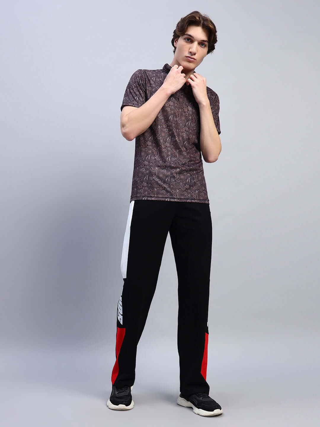 Model wearing Scottish regular fit brown T-shirt made of sports polyester fabric, styled with black and red pants, showcasing casual fashion.