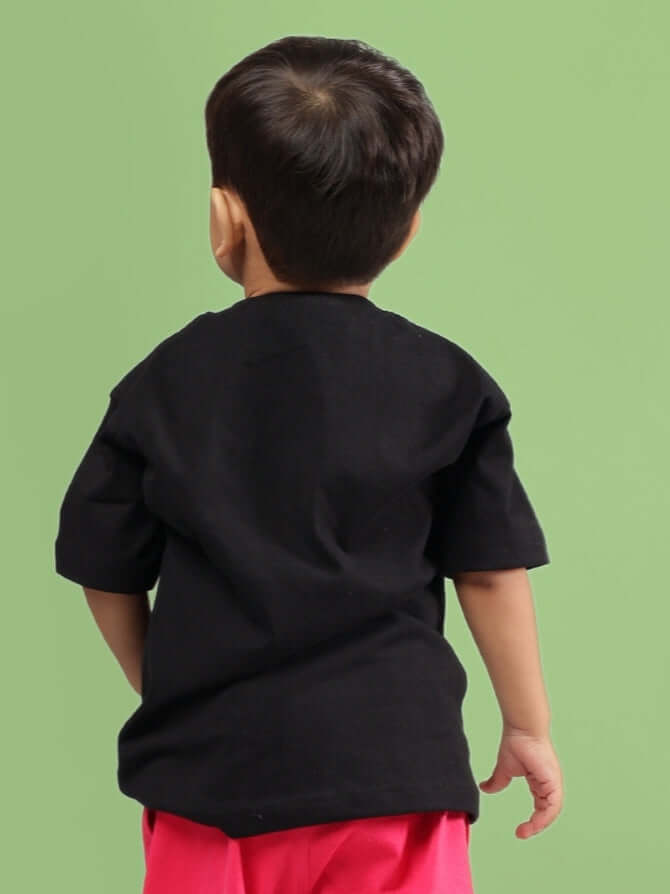 Child wearing SESAME T-SHIRT FOR BOYS GIRLS BLACK, back view on green background.