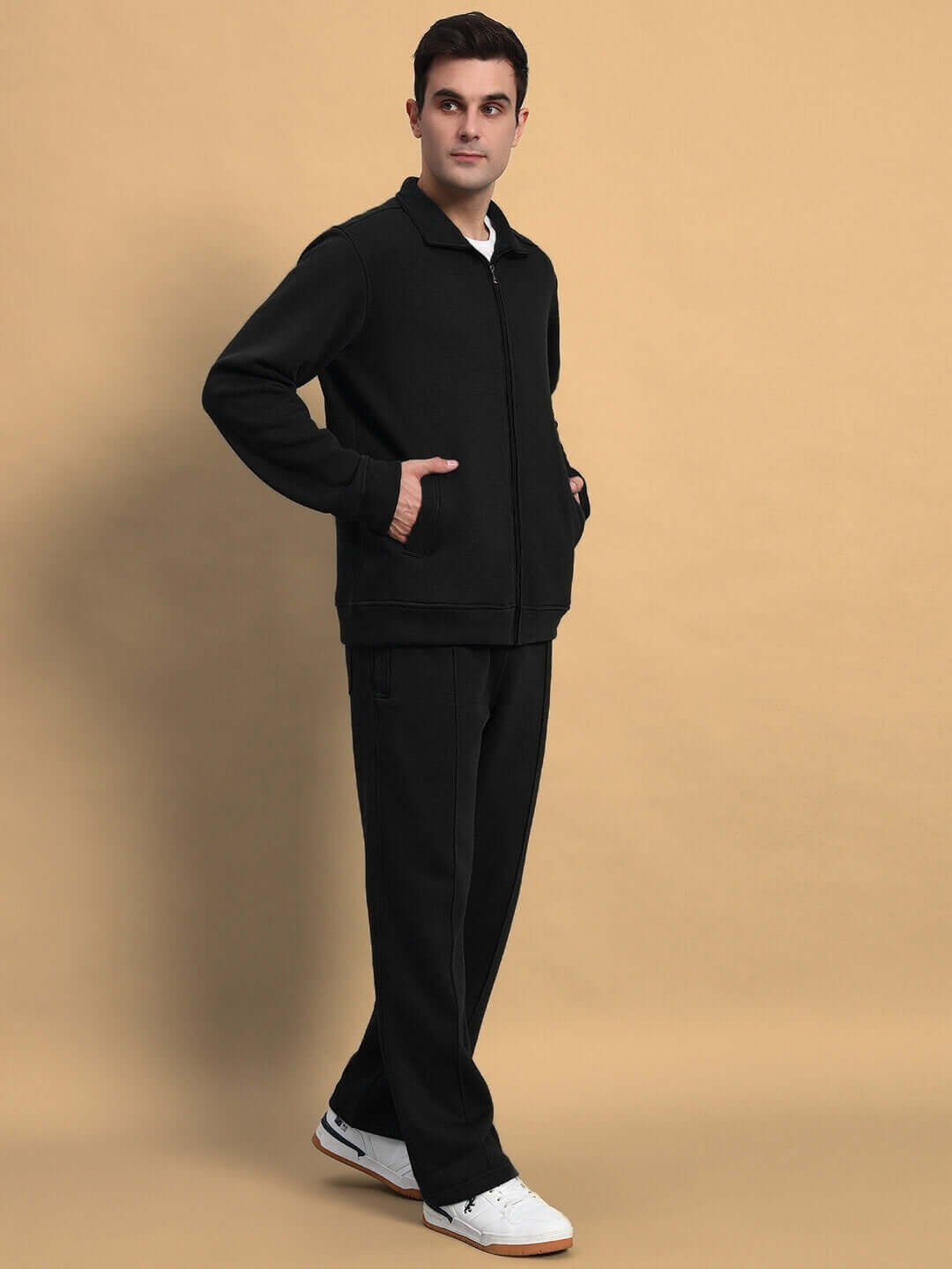 Man wearing SHAGGY ZIPPER FLEECE CO-ORD SET BLACK, standing against beige background.