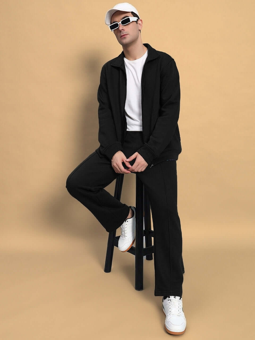 Model wearing SHAGGY ZIPPER FLEECE CO-ORD SET in black, seated stylishly on stool, showcasing DUDS made-to-order fashion.