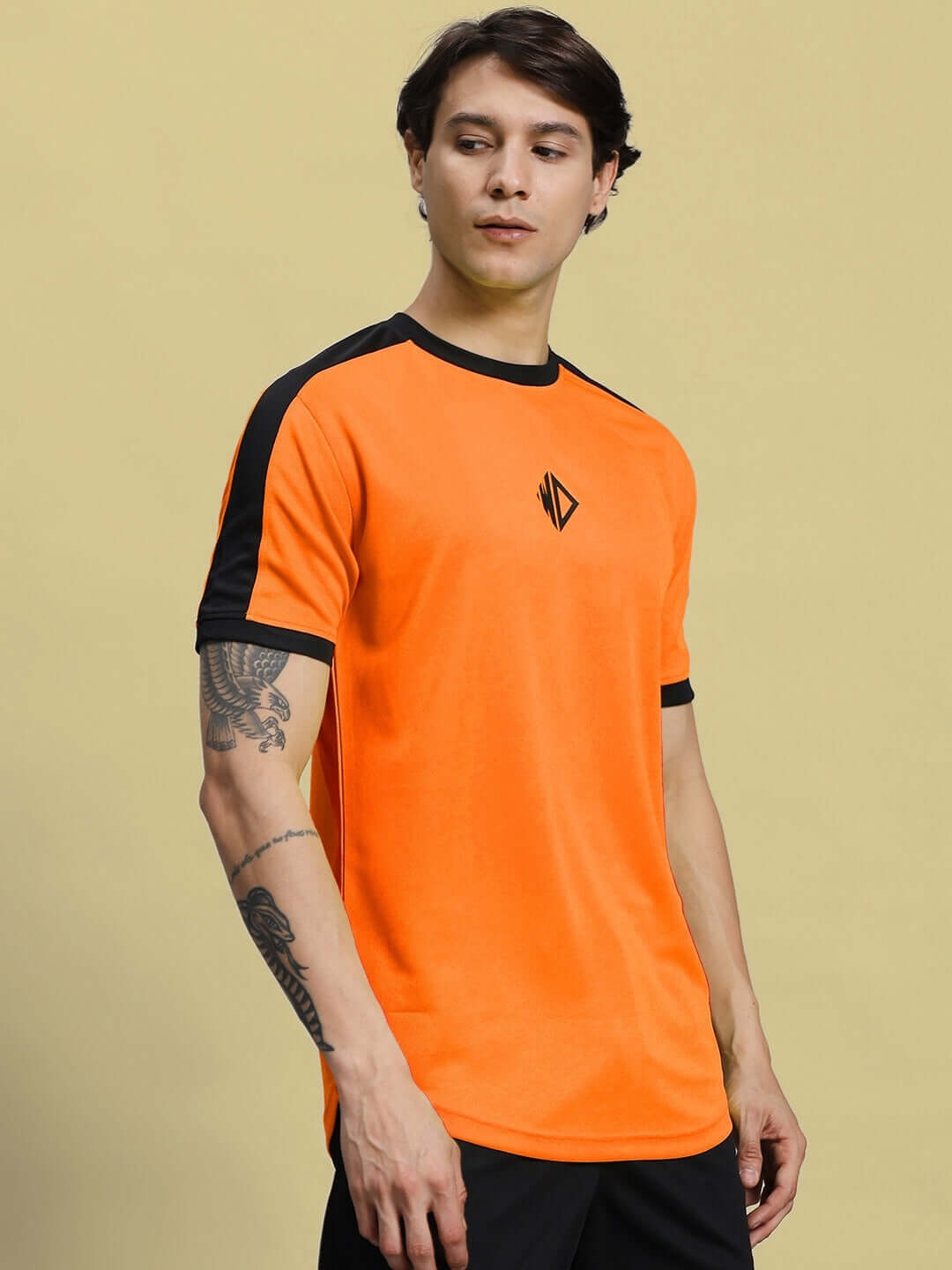 Model wearing SHERPA REGULAR FIT T-SHIRT ORANGE made from sports polyester fabric, ideal for casual and sportswear fashion.