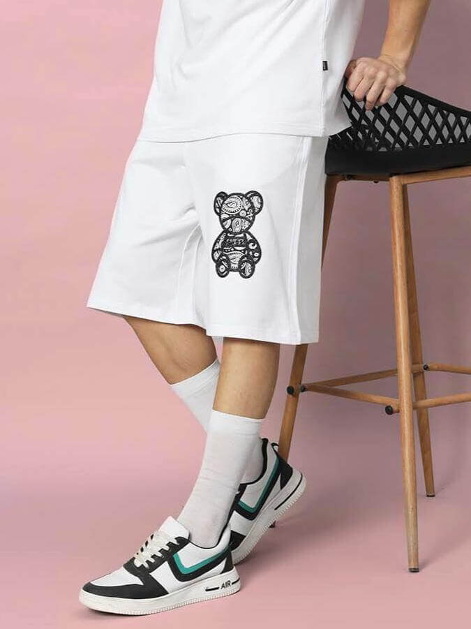 Child wearing SHIMMY REGULAR FIT SHORTS WHITE with bear design, paired with sneakers, showing casual flexibility and style.